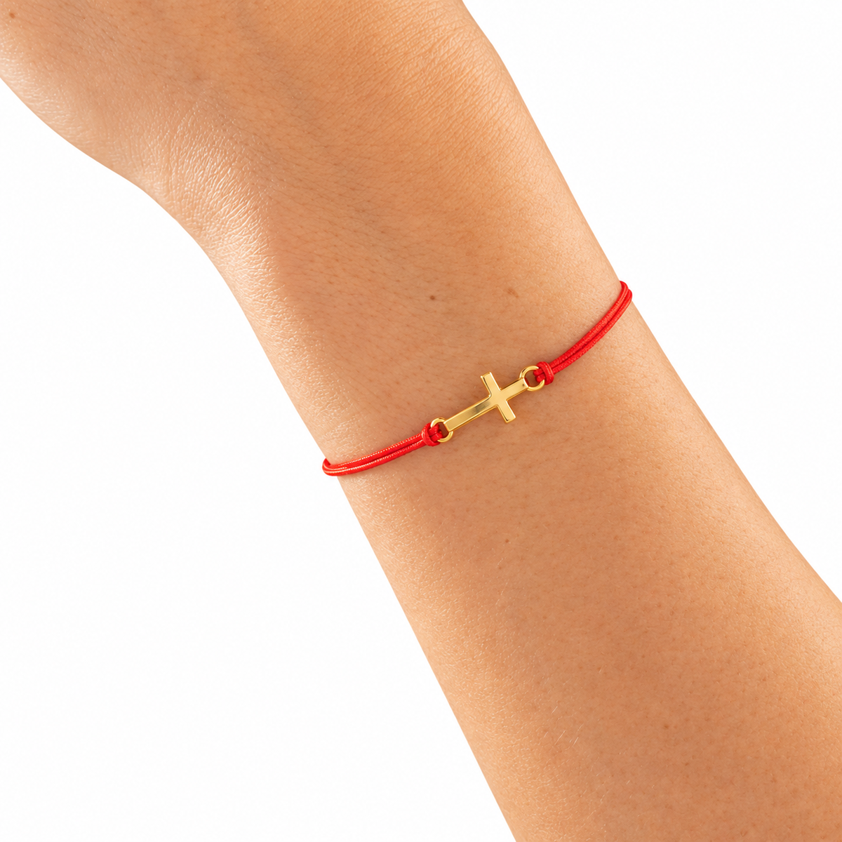 Pulsera Hilo Rojo Cruz Dorada — detalle sobre muñeca, con fondo blanco.