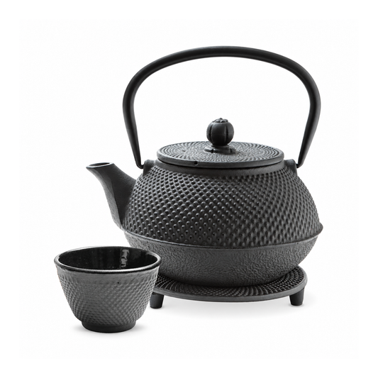 Tetera negra de hierro con una taza y base negra, sobre fondo blanco.